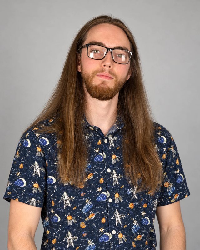 Brady Mayo standing in a space-print shirt against a grey studio backdrop